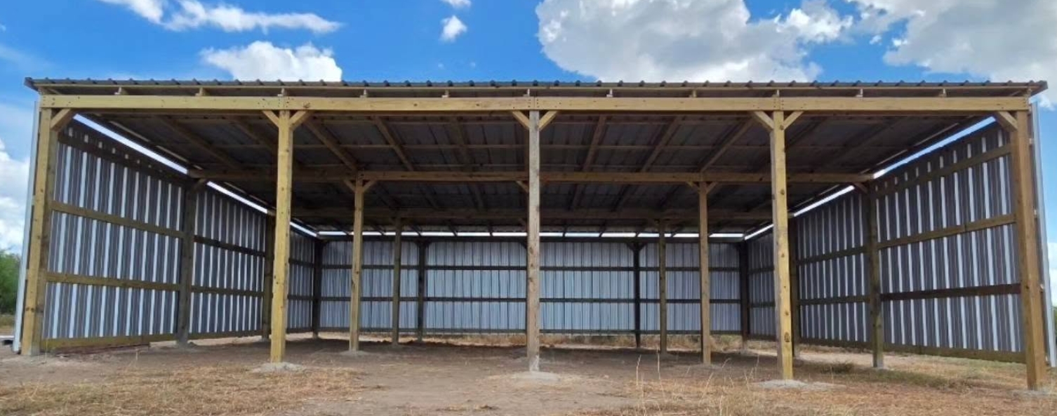 Open-sided pole barn with treated timber posts and a steel roof